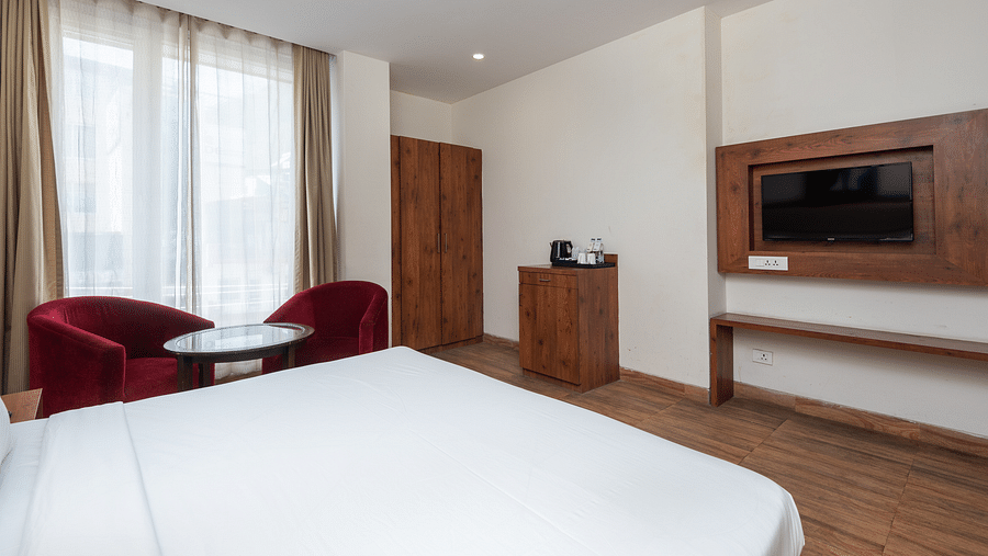 Premium room featuring a television, wooden wardrobe, a tea table with two chairs at DLS The Classio